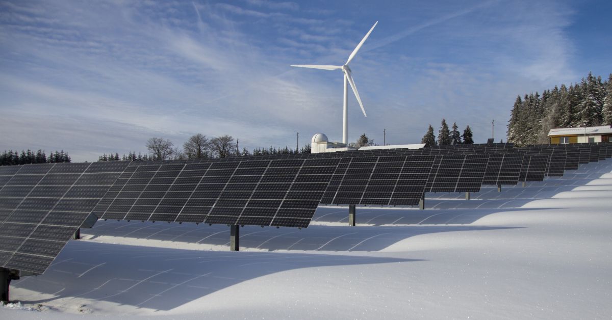 Panneaux solaires dans la neige devant un moulin à vent